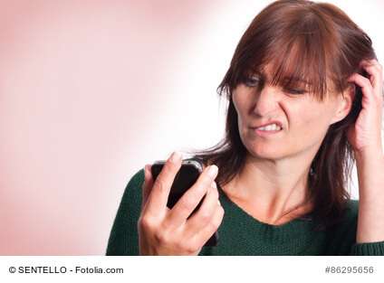 Frau versteht Smartphone nicht und kratzt sich am Hinterkopf